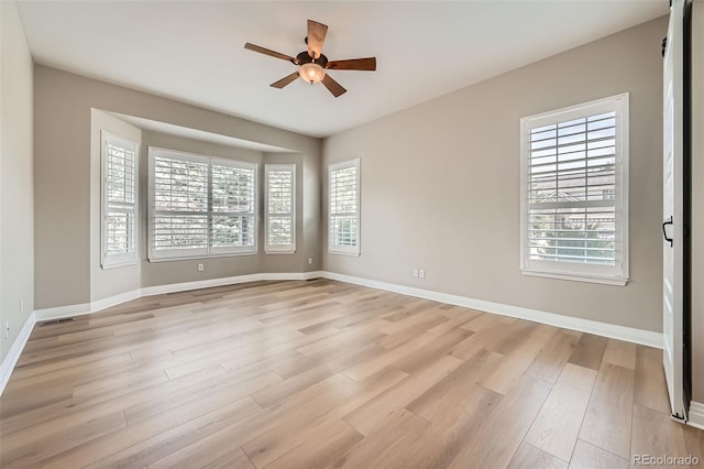 spare room with baseboards, light wood-style flooring, and ceiling fan