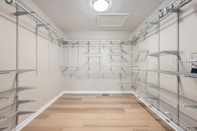spacious closet featuring light wood-style flooring and attic access
