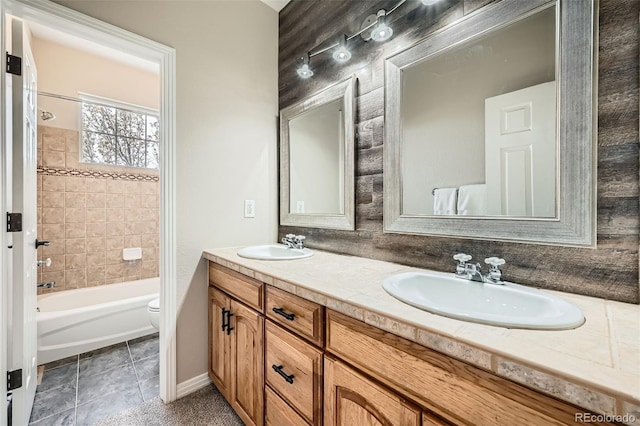 bathroom with double vanity, toilet, a sink, and shower / bathing tub combination