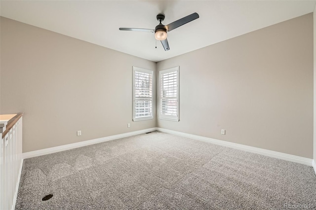 spare room with baseboards, ceiling fan, and light colored carpet