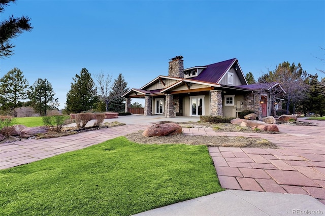 view of front of house featuring a chimney, stone siding, and a front lawn