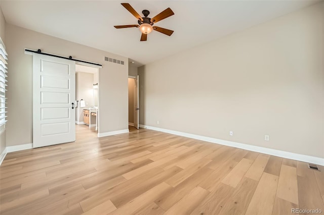 24487 E Frost Dr, Aurora, CO 80016 - unfurnished bedroom featuring a barn door, light wood-style flooring, and baseboards