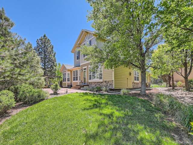 24487 E Frost Dr, Aurora, CO 80016 - back of house featuring stone siding, board and batten siding, and a lawn