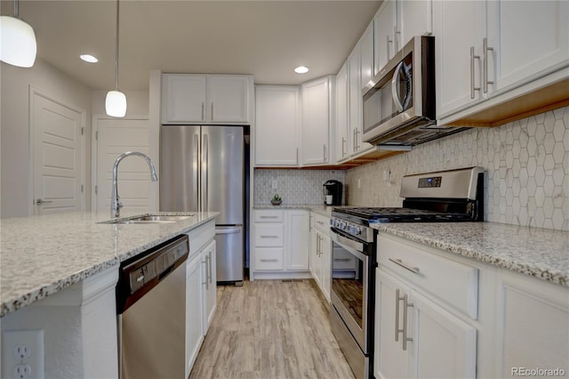 kitchen with appliances with stainless steel finishes, white cabinetry, hanging light fixtures, and sink