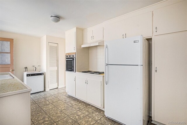 kitchen featuring freestanding refrigerator, dishwasher, under cabinet range hood, decorative backsplash, and oven