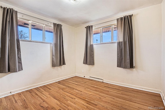 spare room featuring a baseboard radiator, wood finished floors, and baseboards