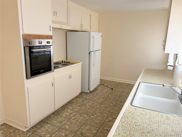 kitchen with appliances with stainless steel finishes, a sink, light countertops, and white cabinetry
