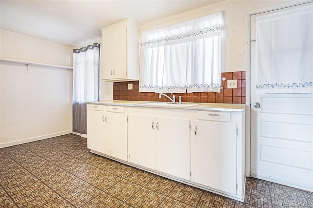 kitchen featuring white cabinetry, a sink, light countertops, and decorative backsplash