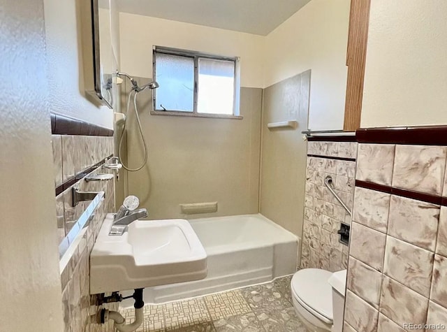 full bath with toilet, tile walls, a sink, and shower / bath combination