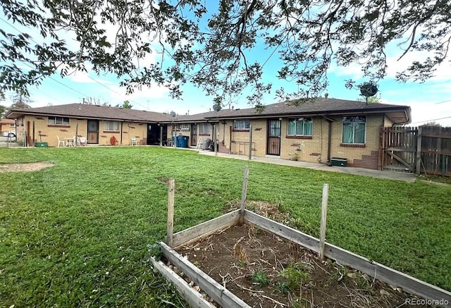 back of property with a vegetable garden, brick siding, and a gate