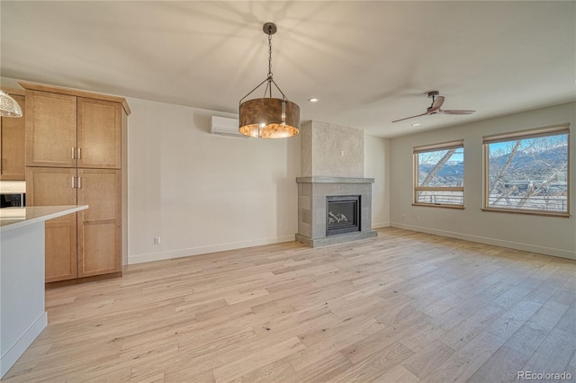 unfurnished living room featuring baseboards, light wood-style floors, a ceiling fan, and a tile fireplace