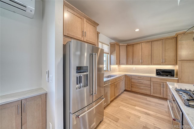 kitchen with a sink, light wood-type flooring, appliances with stainless steel finishes, and light countertops