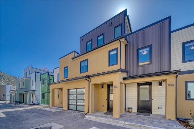 view of front of house featuring stucco siding, a residential view, and a garage