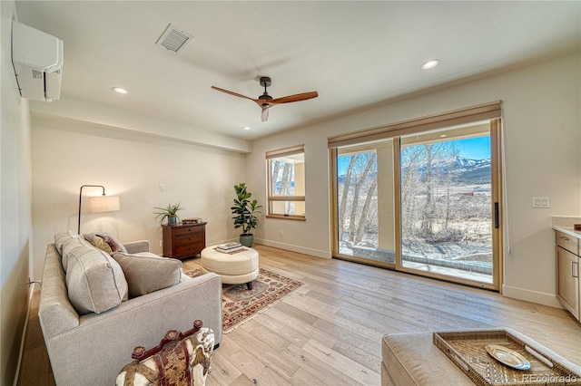 living area with recessed lighting, visible vents, light wood finished floors, and baseboards