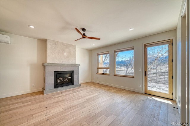 unfurnished living room featuring light wood-style flooring, a fireplace, baseboards, and a healthy amount of sunlight