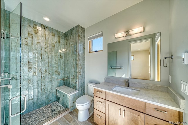 bathroom featuring vanity, toilet, a stall shower, and wood finish floors