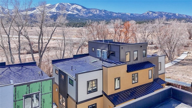 exterior space with a standing seam roof, stucco siding, a mountain view, and metal roof