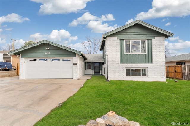 split level home featuring driveway, a front lawn, fence, a garage, and brick siding