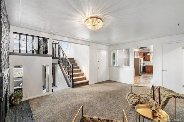 carpeted living room featuring baseboards, stairs, and an inviting chandelier