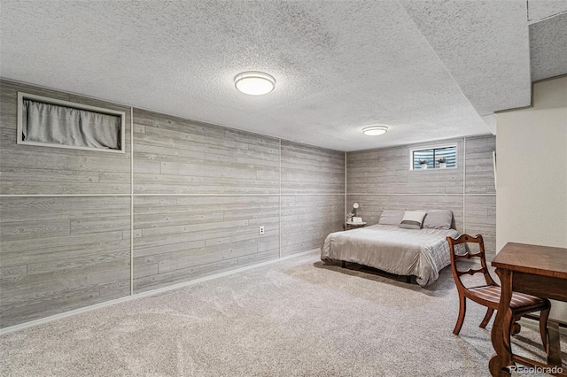 bedroom featuring wooden walls, a textured ceiling, and carpet flooring