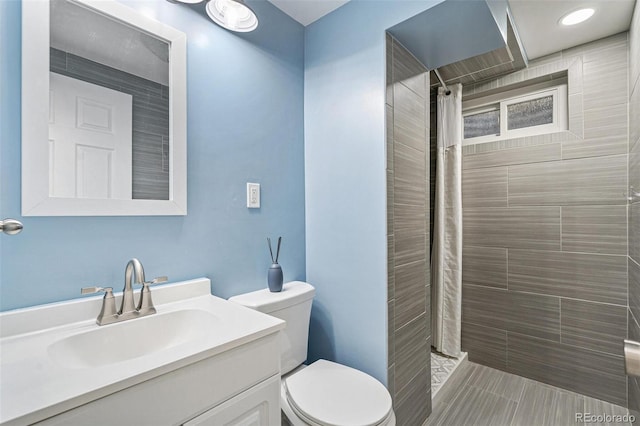 bathroom featuring a tile shower, toilet, and vanity