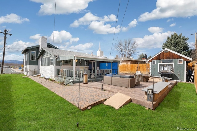 rear view of property with an outdoor living space, a shed, a yard, an outbuilding, and a patio