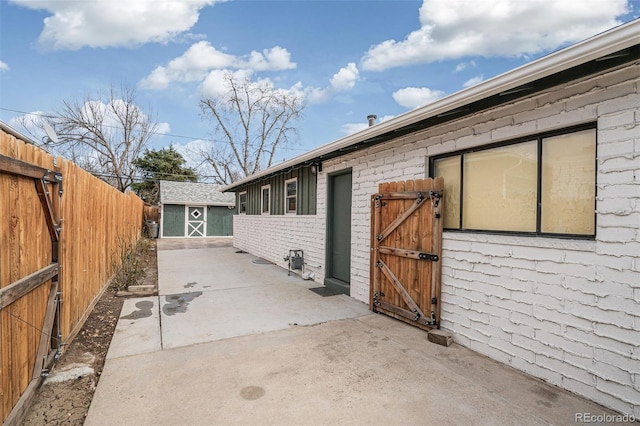 view of patio / terrace featuring a storage shed, an outbuilding, a gate, and a fenced backyard