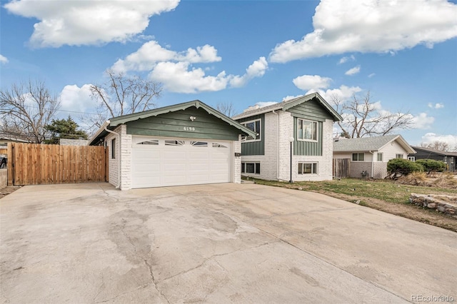 view of front of property with concrete driveway, fence, and brick siding