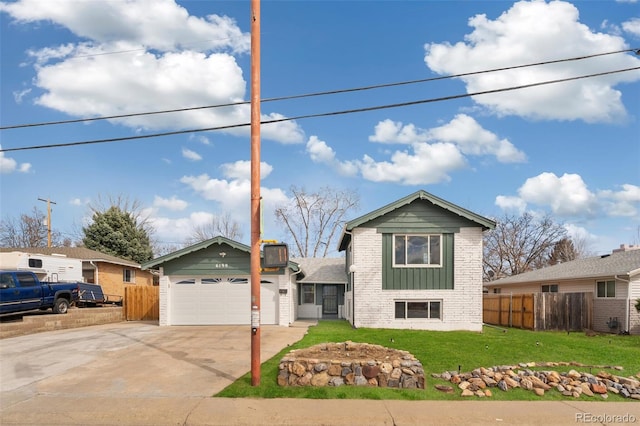 split level home with a garage, brick siding, driveway, and fence