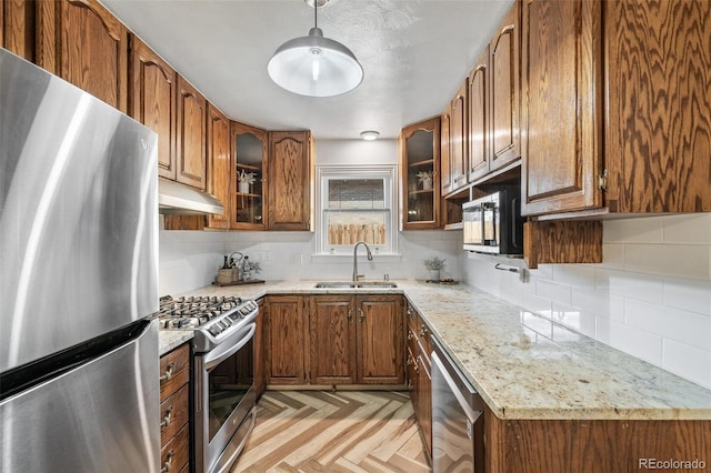 6190 Garrison St, Arvada, CO 80004 - kitchen featuring stainless steel appliances, a sink, under cabinet range hood, and brown cabinets