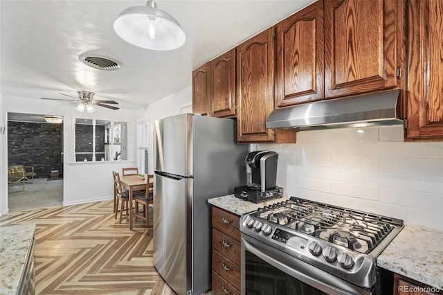 6190 Garrison St, Arvada, CO 80004 - kitchen with stainless steel appliances, range hood, decorative backsplash, a ceiling fan, and light stone countertops