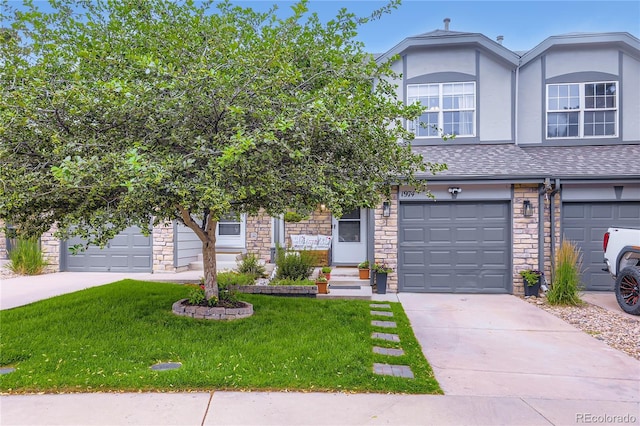 1974 E 102nd Cir, Thornton, CO 80229 - townhome / multi-family property featuring a front yard, stone siding, concrete driveway, a shingled roof, and stucco siding