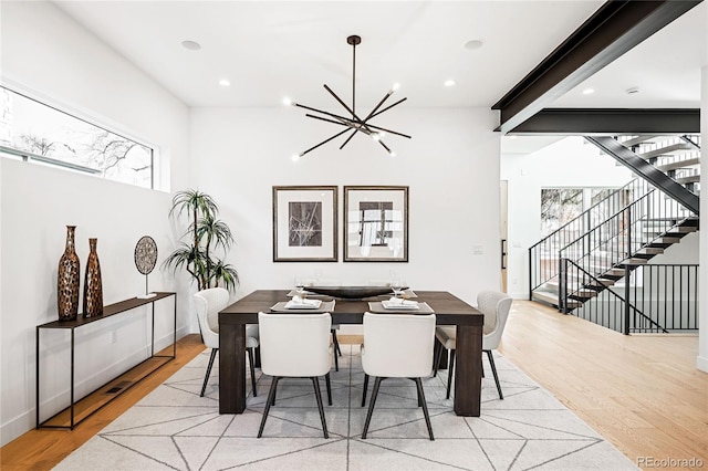 dining room featuring beam ceiling, plenty of natural light, an inviting chandelier, and light hardwood / wood-style flooring