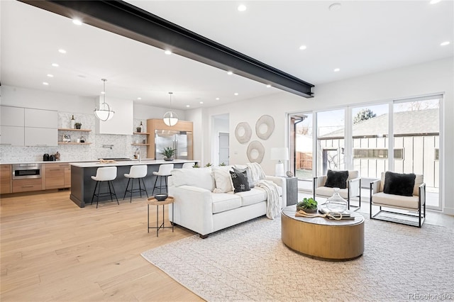 living room with beamed ceiling, light wood-type flooring, and sink