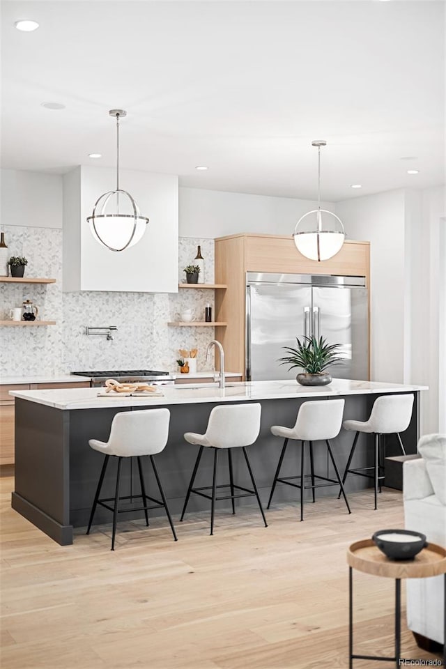 kitchen with pendant lighting, stainless steel appliances, and light hardwood / wood-style floors