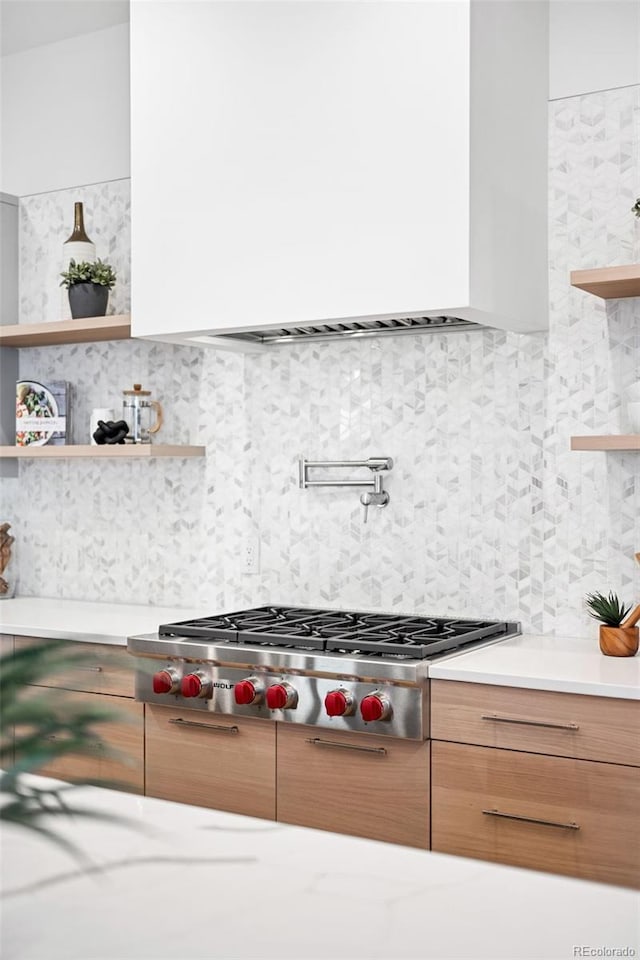 kitchen with stainless steel gas stovetop and backsplash