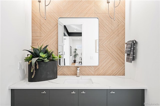 bar with gray cabinetry, light stone countertops, and sink