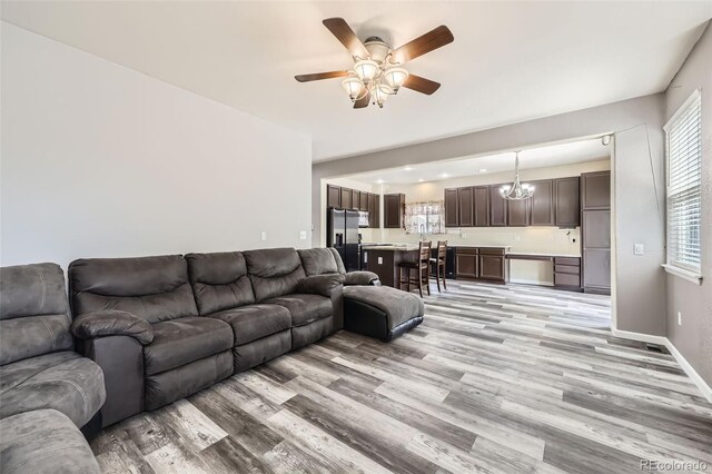 334 Octillo St, Brighton, CO 80601 - living area featuring light wood finished floors, ceiling fan, a chandelier, and baseboards