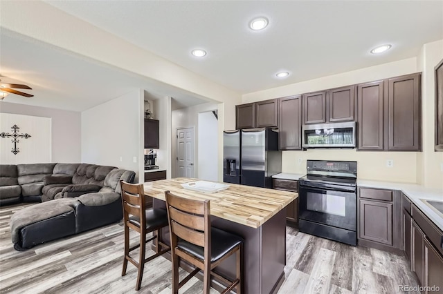 334 Octillo St, Brighton, CO 80601 - kitchen with stainless steel appliances, a breakfast bar, light wood-style flooring, open floor plan, and dark brown cabinetry