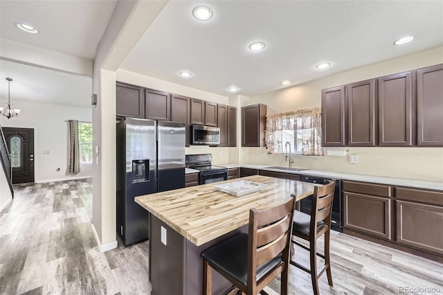 334 Octillo St, Brighton, CO 80601 - kitchen featuring appliances with stainless steel finishes, a sink, dark brown cabinetry, a kitchen bar, and recessed lighting