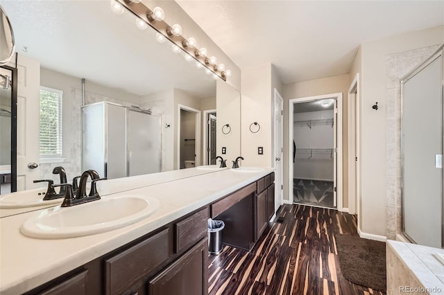 334 Octillo St, Brighton, CO 80601 - full bathroom featuring a shower stall, wood finished floors, double vanity, a walk in closet, and baseboards