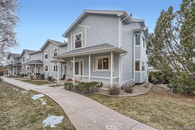 view of front facade with covered porch, a front yard, and cooling unit