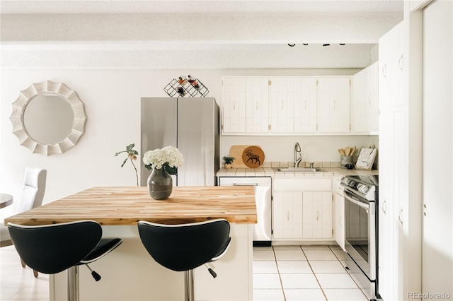 1365 Columbine St Unit 204, Denver, CO 80206 - kitchen with appliances with stainless steel finishes, a sink, tile counters, light tile patterned floors, and white cabinets