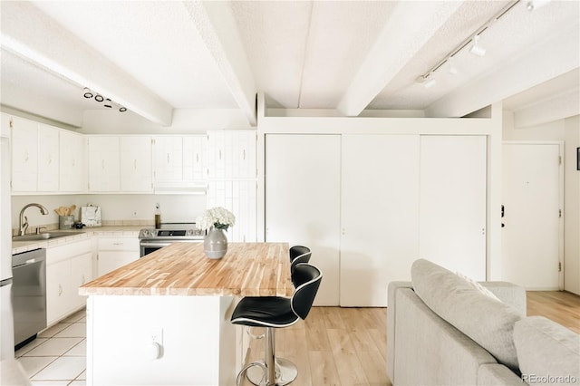 1365 Columbine St Unit 204, Denver, CO 80206 - kitchen featuring a sink, appliances with stainless steel finishes, light countertops, beam ceiling, and a kitchen island