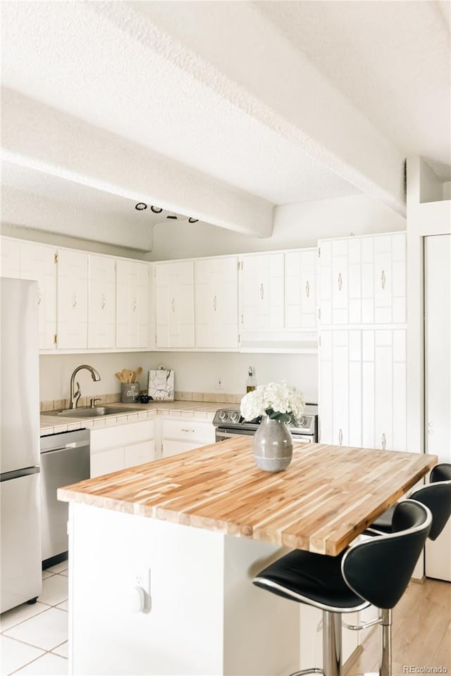 1365 Columbine St Unit 204, Denver, CO 80206 - kitchen featuring appliances with stainless steel finishes, butcher block counters, white cabinets, and a kitchen breakfast bar