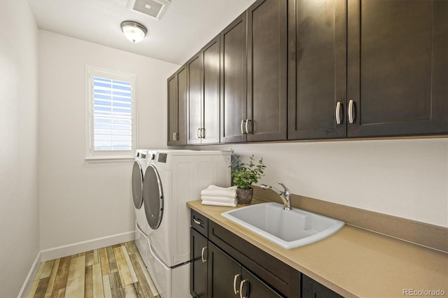 laundry room with washing machine and dryer, sink, cabinets, and hardwood / wood-style floors