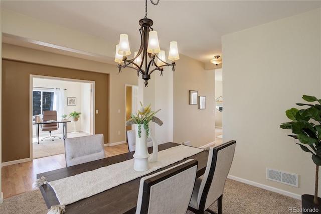 dining area with visible vents, baseboards, a notable chandelier, and light wood-style flooring