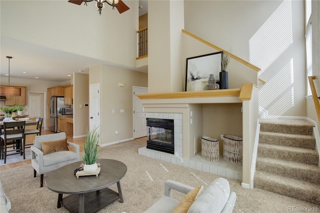 living room with stairway, baseboards, a healthy amount of sunlight, and a tile fireplace