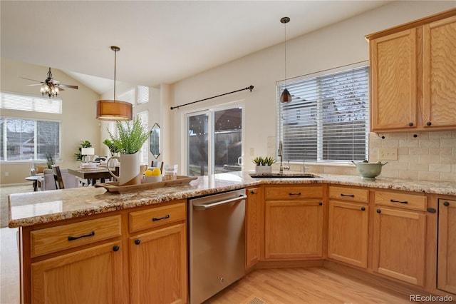 kitchen with vaulted ceiling, a sink, light stone countertops, and stainless steel dishwasher