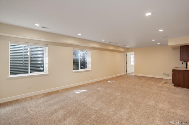 unfurnished living room featuring a sink, visible vents, baseboards, and recessed lighting